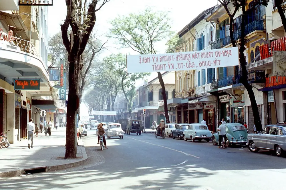 Tree-lined Tự Do Street in Saigon in 1968, with shopfronts and parked cars