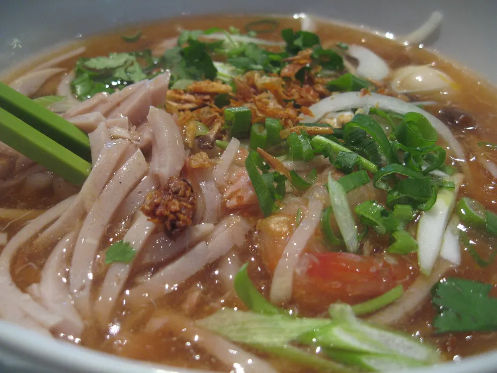 Bowl of bánh canh noodle soup with crab and herbs