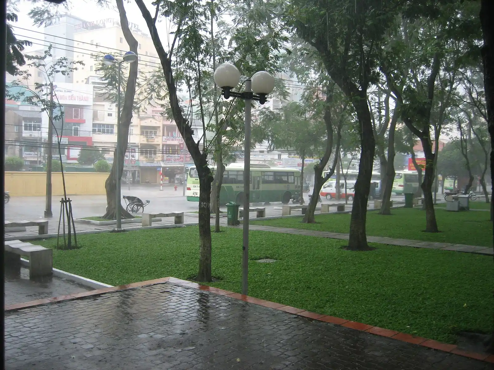Rain falling on a wet park path and lawn in Saigon