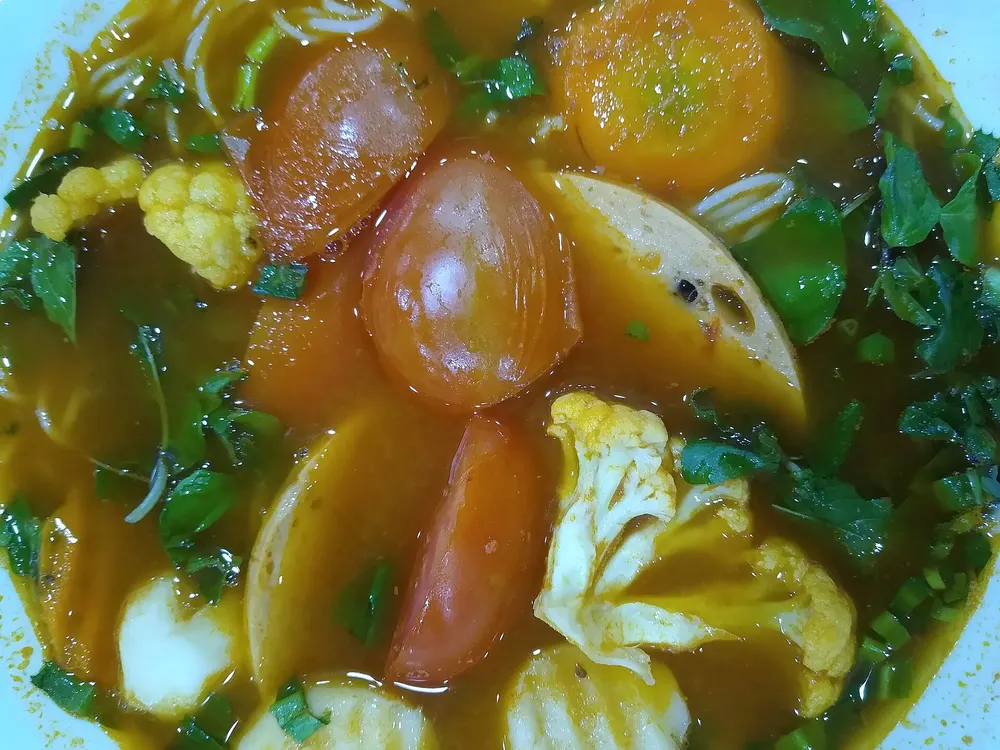 Bowl of vegetarian bún riêu noodle soup with tomato and tofu