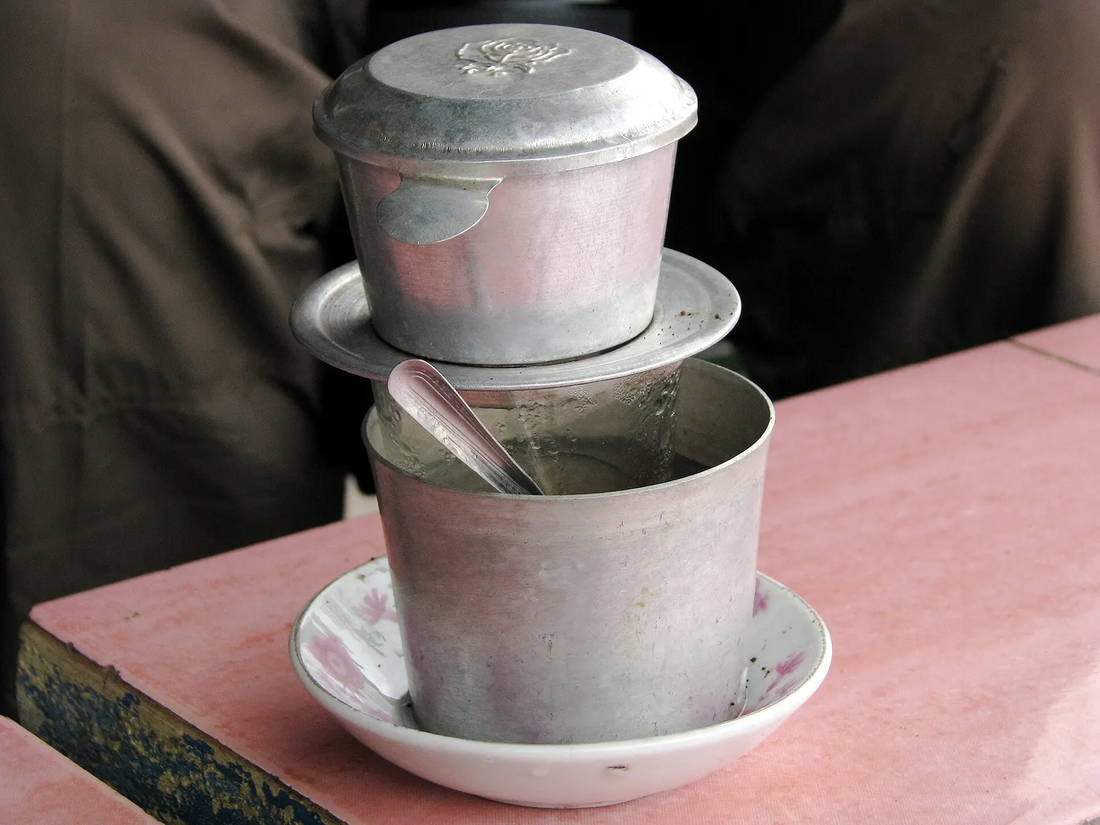 Vietnamese coffee dripping through a metal phin filter into a cup, photographed in Vietnam