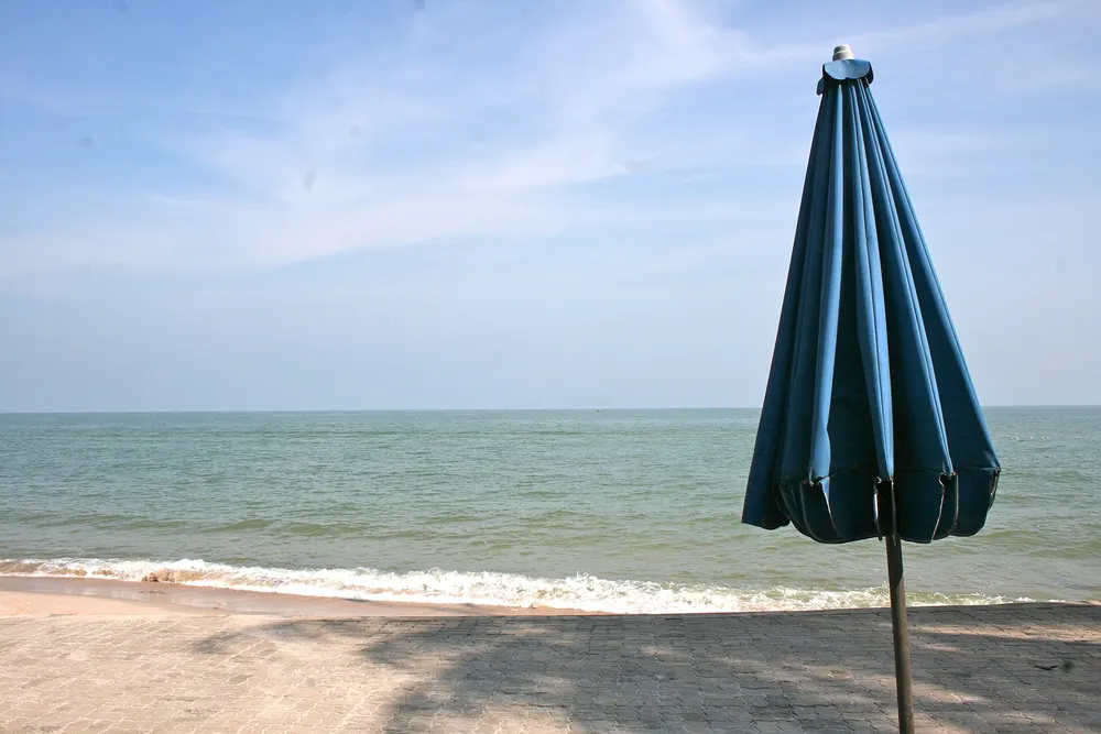 Folded sun umbrella standing on a beach by the sea