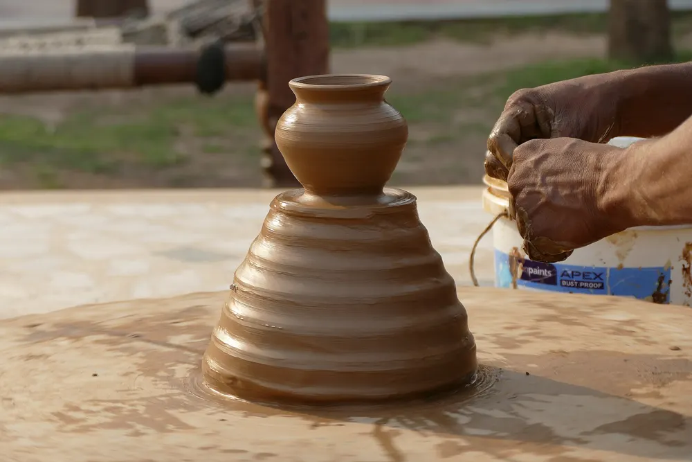 Hands shaping clay on a potter's wheel