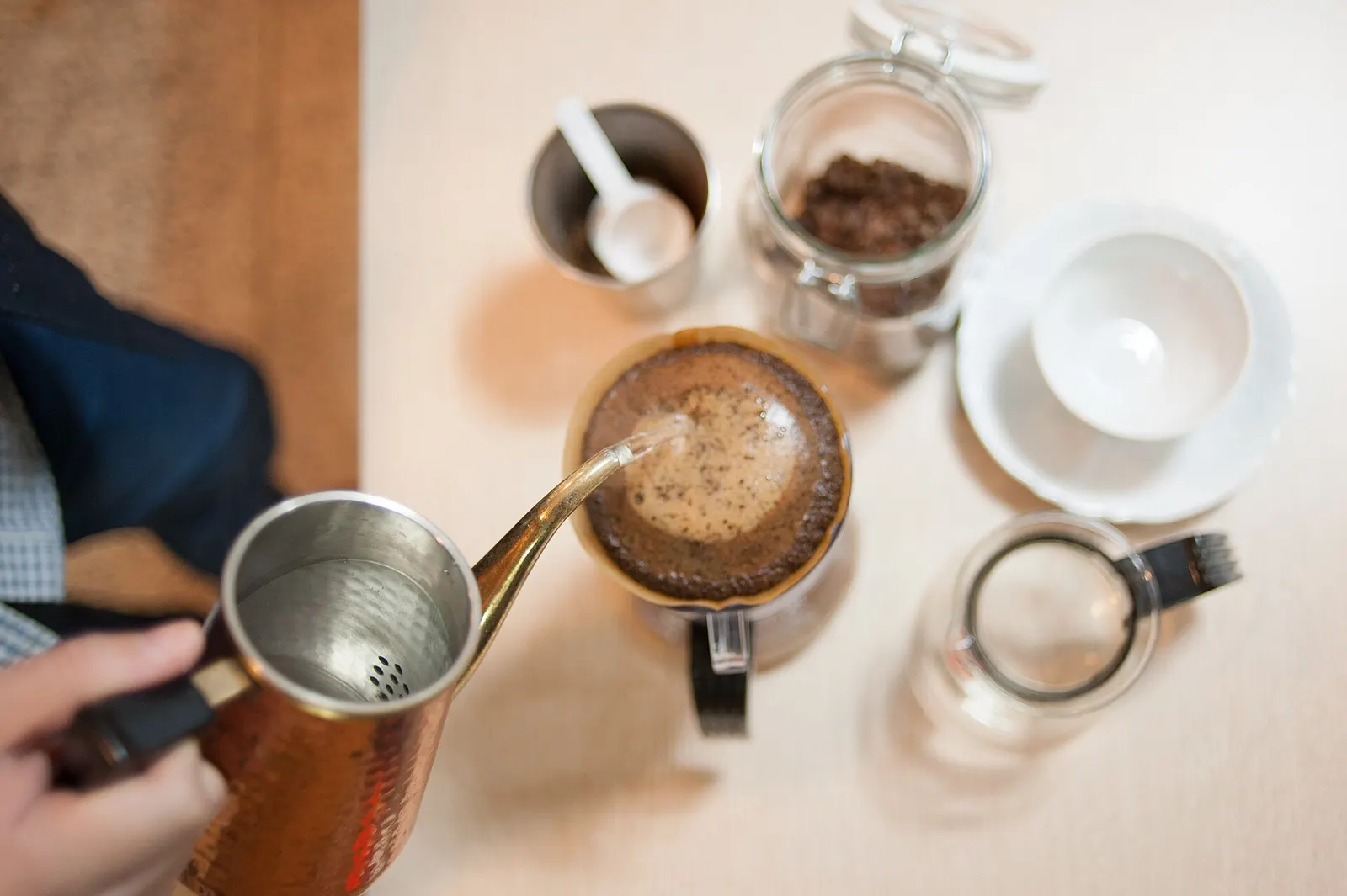 Hand pouring hot water into a pour-over coffee dripper