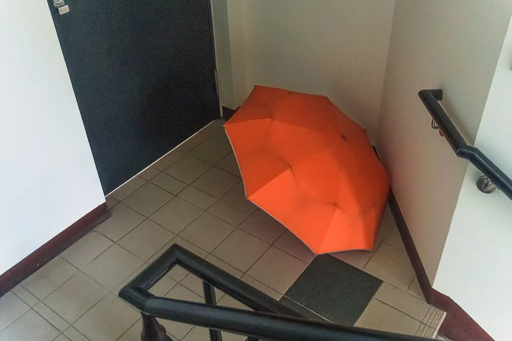 Orange folding umbrella drying on a stairwell floor