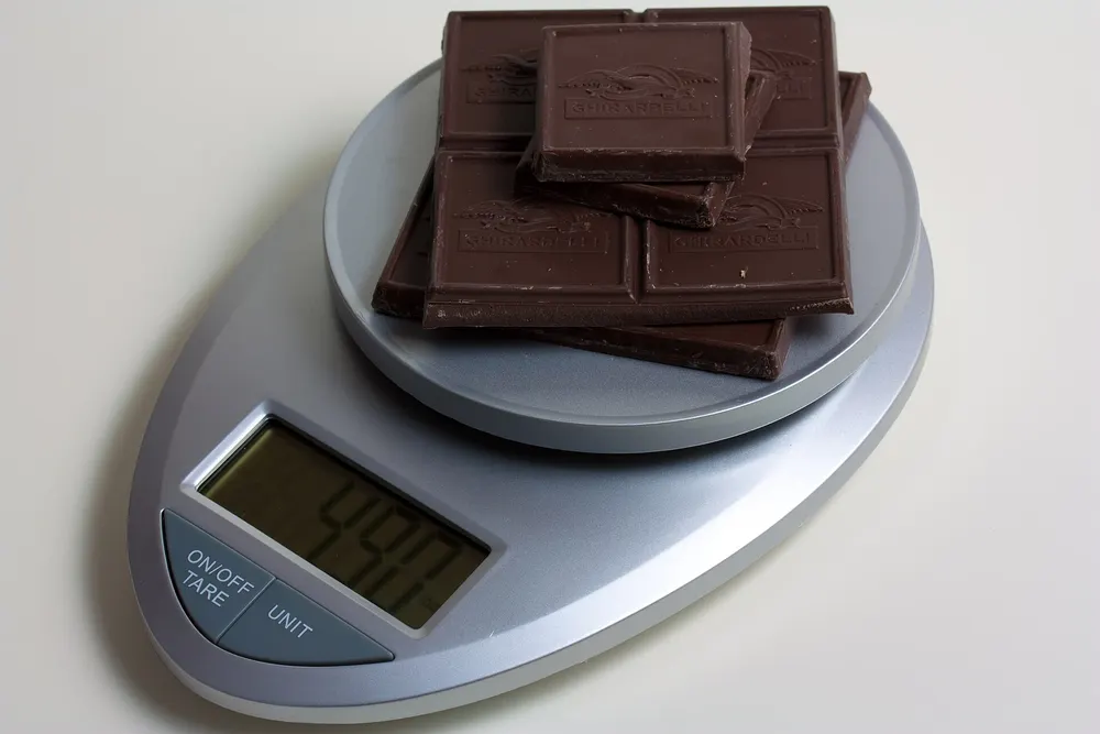 Digital kitchen scale weighing pieces of chocolate