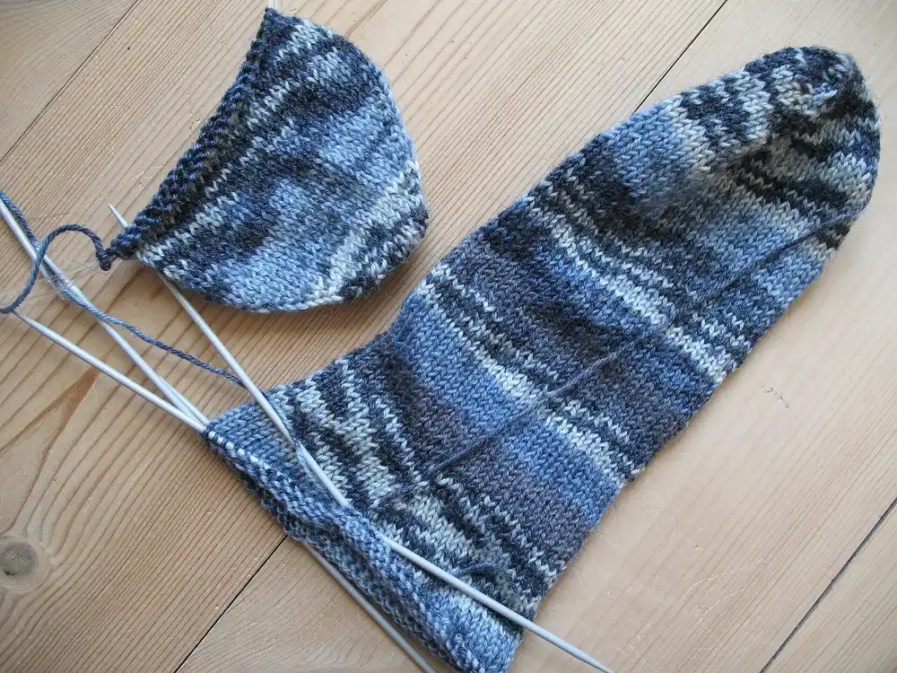 Blue sock being knitted on double-pointed needles