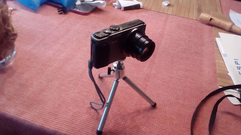 Compact camera mounted on a small tripod on a table