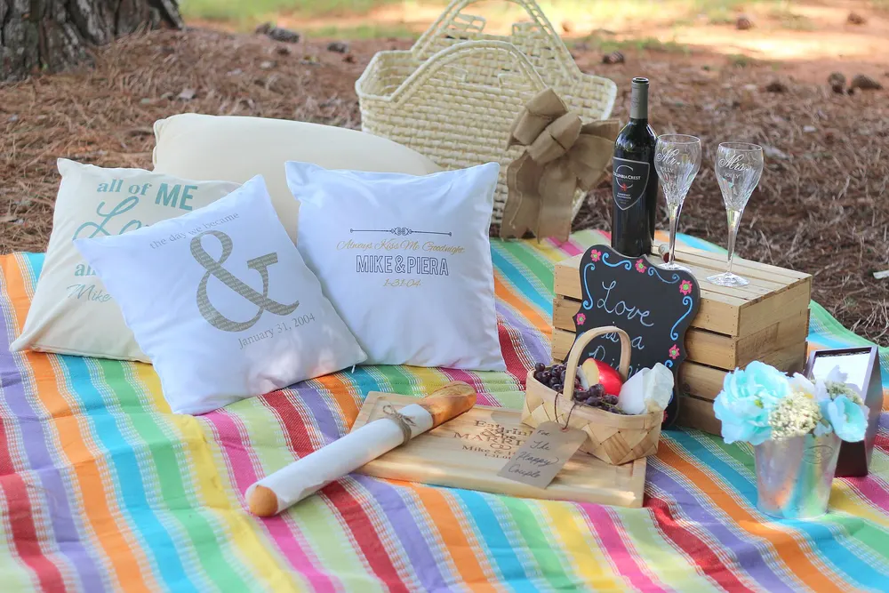 Picnic blanket with glasses, cheese and fruit on a wooden board