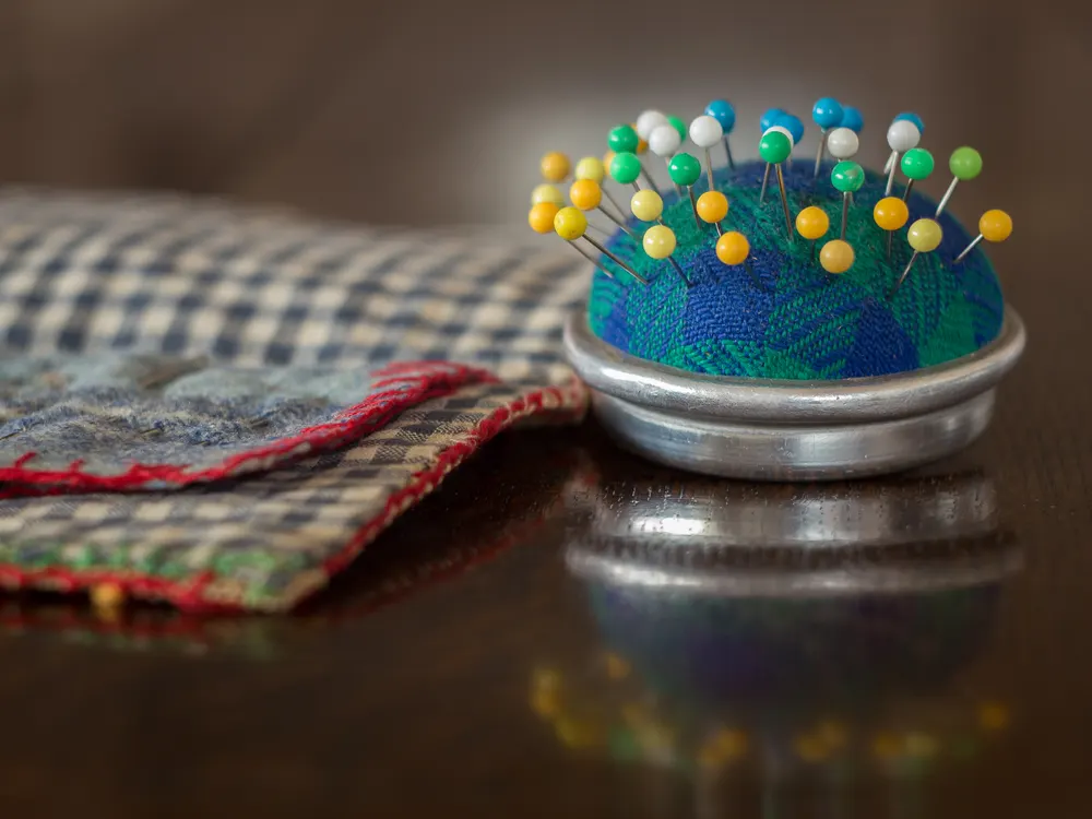 Pincushion full of coloured pins on fabric